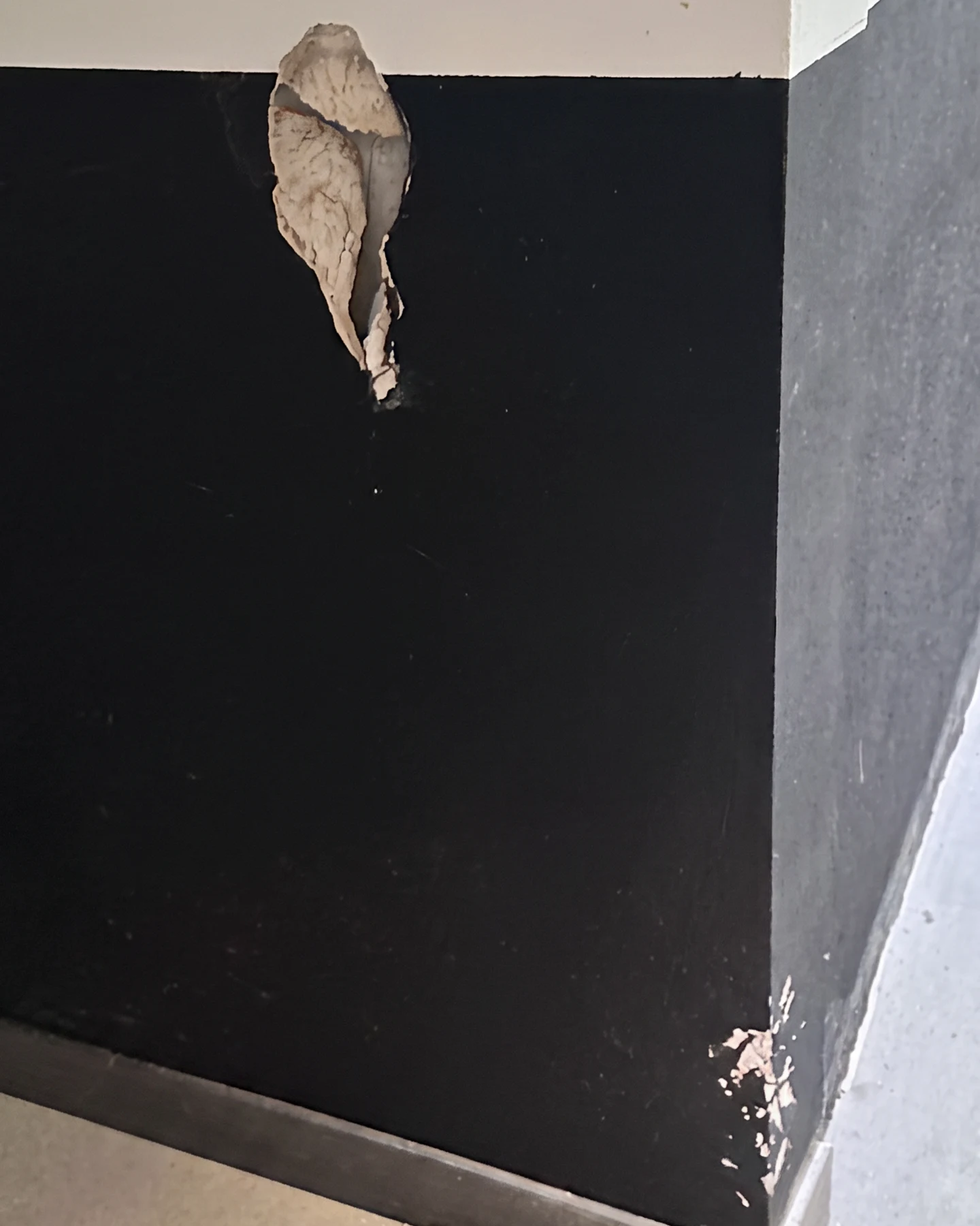 Damaged drywall and chipped corner in an apartment building corridor before repair