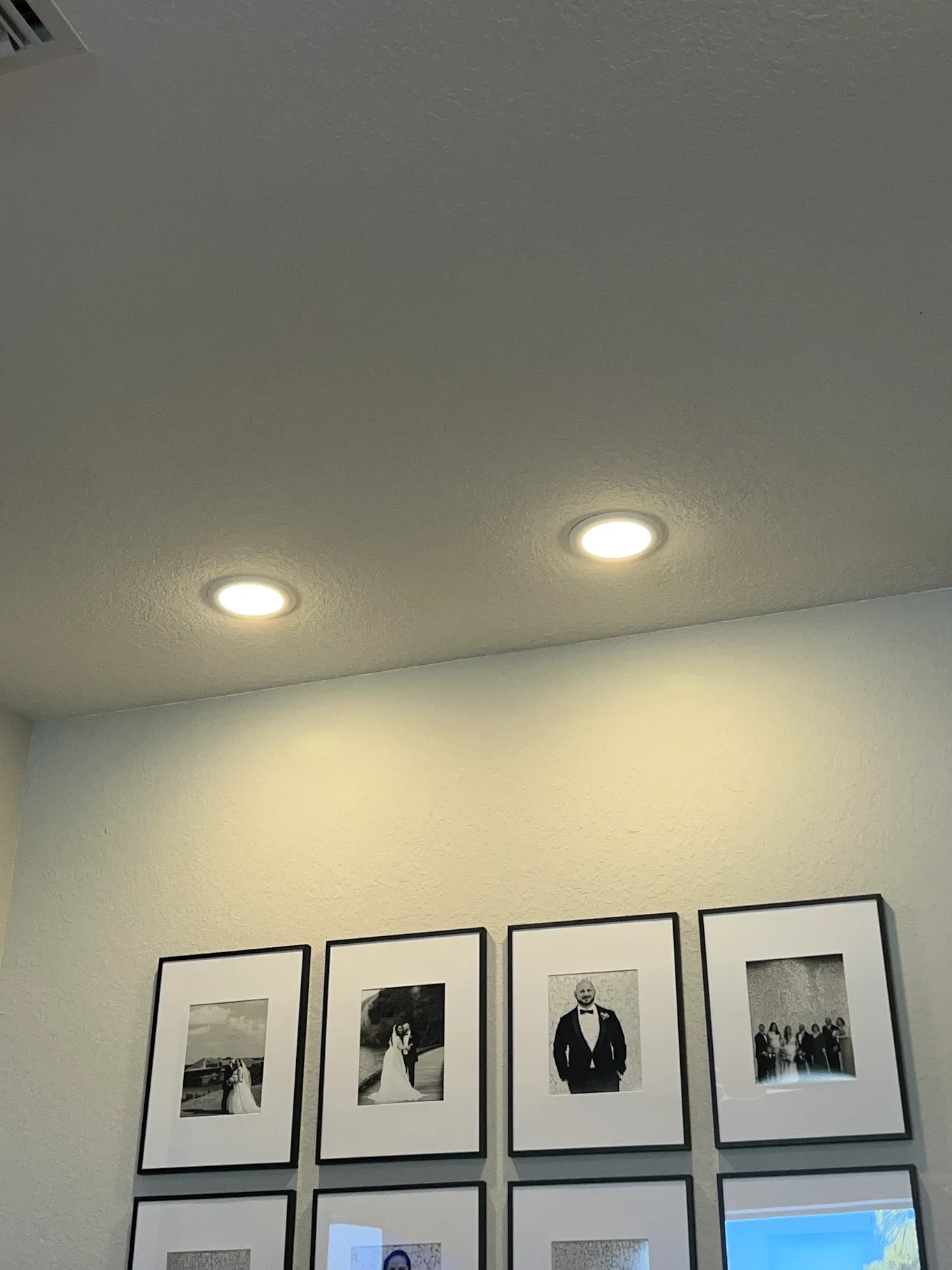 Recessed pot lights installed above a gallery wall in a rental unit